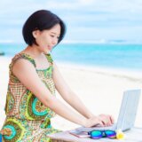 南国の海でノートパソコンを使う女性