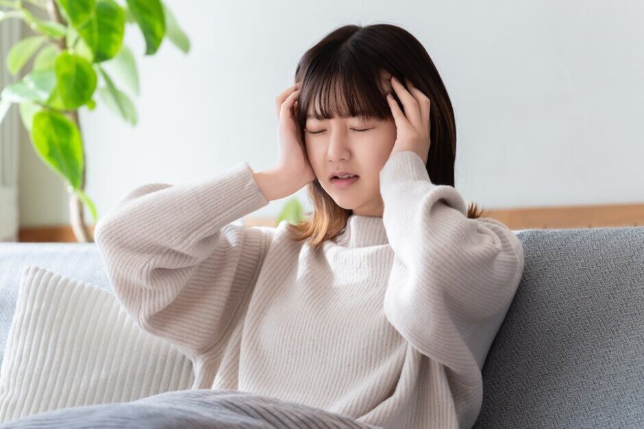 頭を押さえて悩む女性