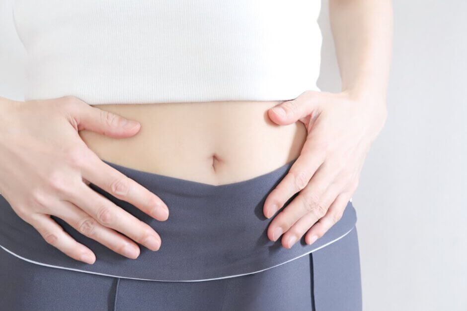 お腹を押さえる女性の手元